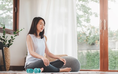 Asian woman doing yoga meditation at home